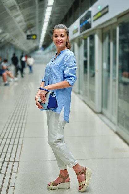 Jovem mulher com bolsa na estação de metrô.