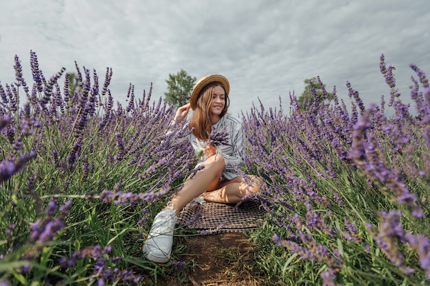 Jovem mulher com buquê de lavanda no fundo do campo de flores violetas