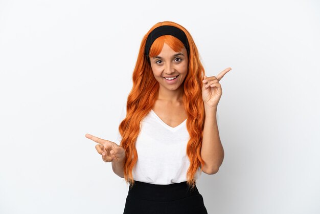 Jovem mulher com cabelo laranja isolado no fundo branco apontando o dedo para as laterais e feliz
