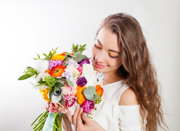 Jovem mulher com cabelo longo encaracolado desfrutando de buquê de flores feliz dia da mulher