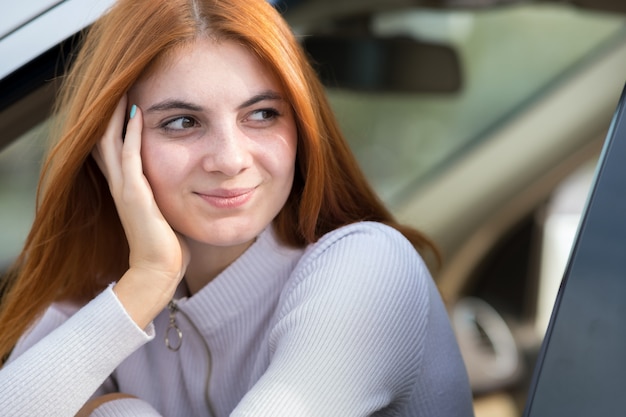 Jovem mulher com cabelo vermelho, dirigindo um carro