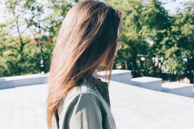 Jovem mulher com cabelos castanhos compridos, passeios no parque no verão