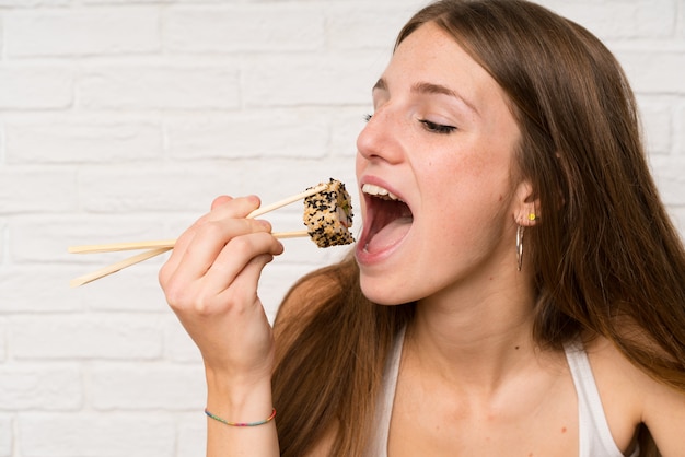 Foto jovem mulher com cabelos longos, comer sushi