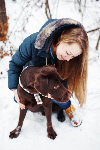 Jovem mulher com cachorro labrador na floresta de inverno