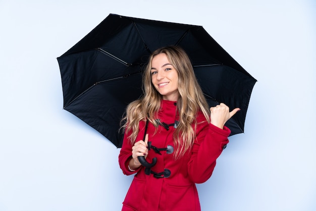 Jovem mulher com casaco de inverno e segurando um guarda-chuva apontando para o lado para apresentar um produto