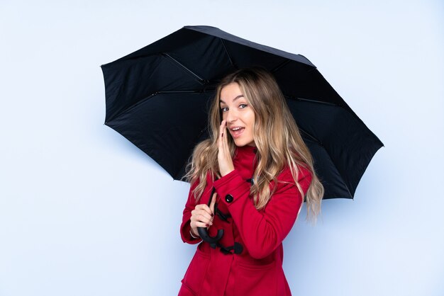 Jovem mulher com casaco de inverno e segurando um guarda-chuva sussurrando algo