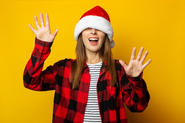 Jovem mulher com chapéu de Papai Noel e camisa xadrez vermelha