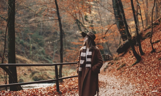 Jovem mulher com chapéu em um parque de temporada outono