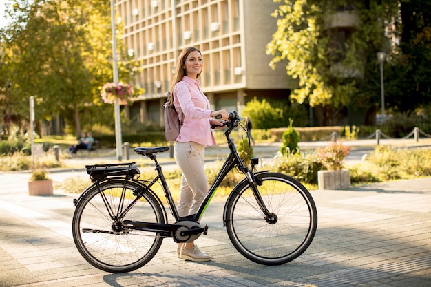 Jovem mulher com cidade moderna e-bike elétrica limpa transporte urbano sustentável