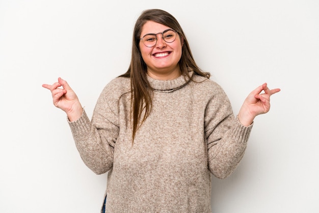 Jovem mulher com excesso de peso caucasiana isolada em fundo branco apontando para diferentes espaços de cópia escolhendo um deles mostrando com o dedo