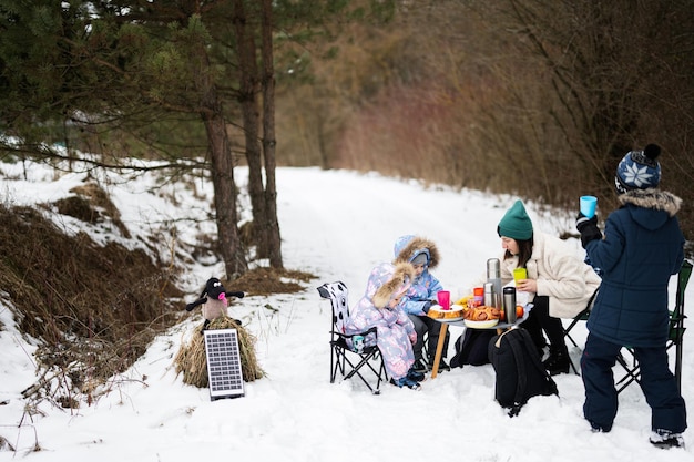 Jovem mulher com filhos na floresta de inverno em um piquenique Mãe e três filhos