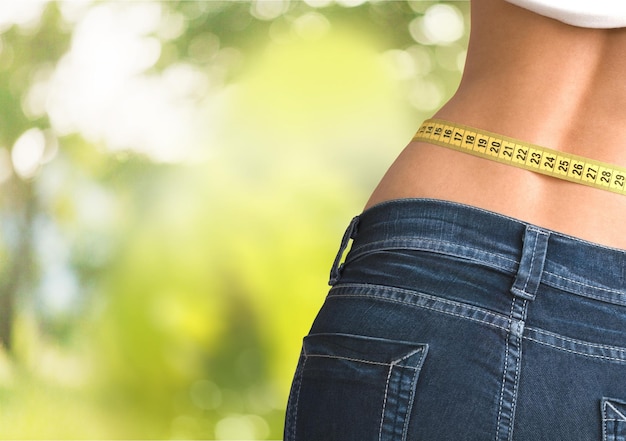 Jovem mulher com fita métrica na barriga