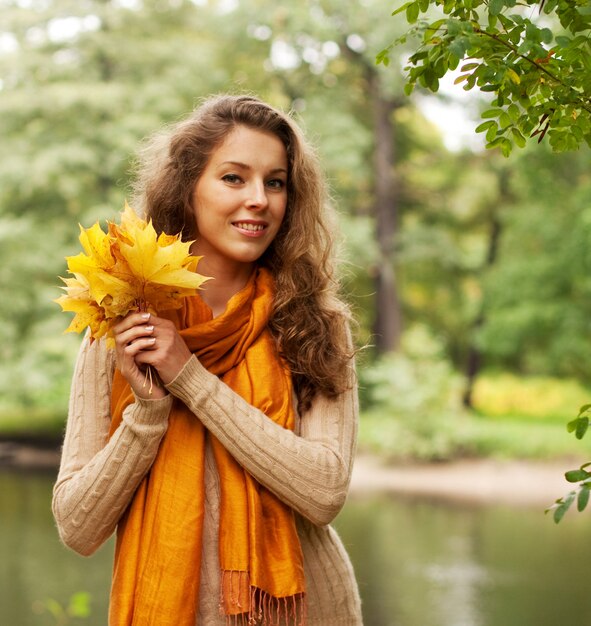 Jovem mulher com folhas de outono no parque
