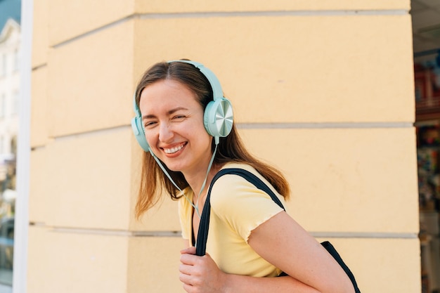 Jovem mulher com fones de ouvido de menta e boné preto lá fora na rua