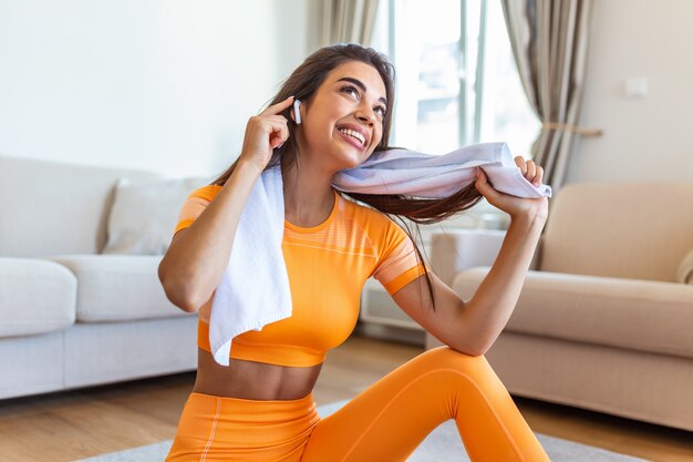 Jovem mulher com fones de ouvido, descansando após o treino.