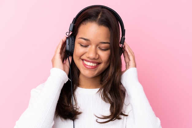 Jovem mulher com fones de ouvido sobre parede rosa isolada