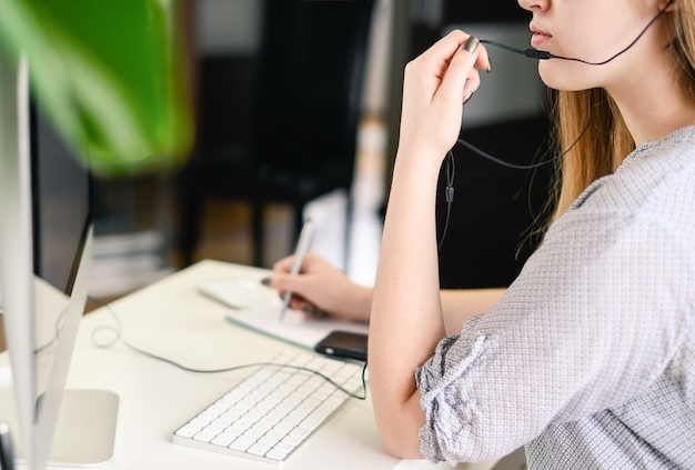 Foto jovem mulher com fones de ouvido, trabalhando, aprendendo, falando no computador. foto de alta qualidade