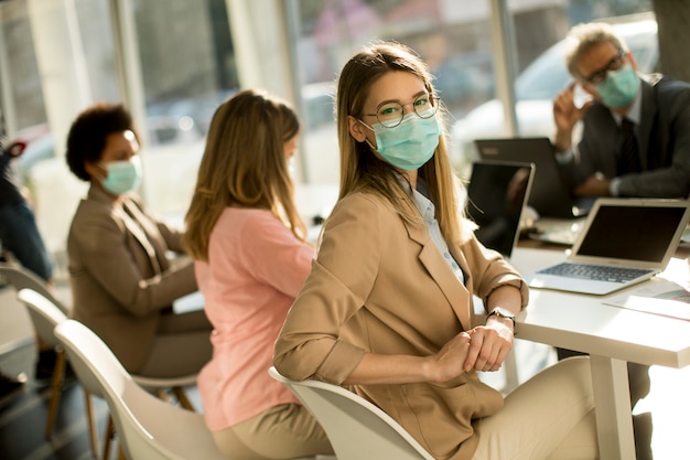Jovem mulher com grupo de empresários tem uma reunião e trabalhando no escritório e usar máscara como proteção contra o vírus da coroa