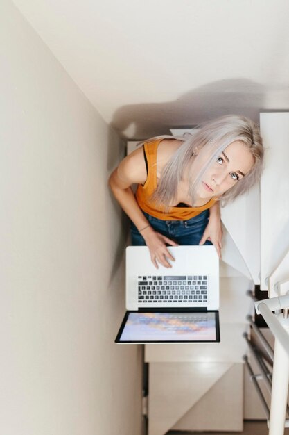 Jovem mulher com laptop na escada em casa