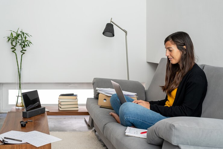 Foto jovem mulher com laptop telecommuting no sofá em sua casa