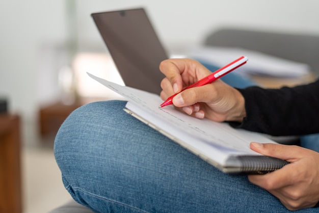 Foto jovem mulher com laptop telecommuting no sofá em sua casa