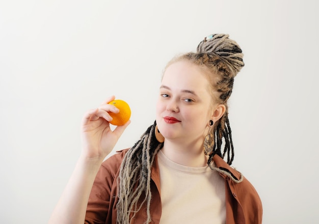 Jovem mulher com laranja no fundo branco