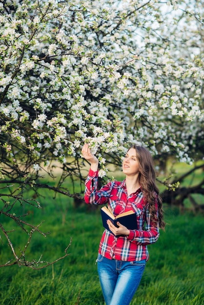 Jovem mulher com livro em um jardim florescendo