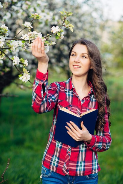 Jovem mulher com livro em um jardim florescendo