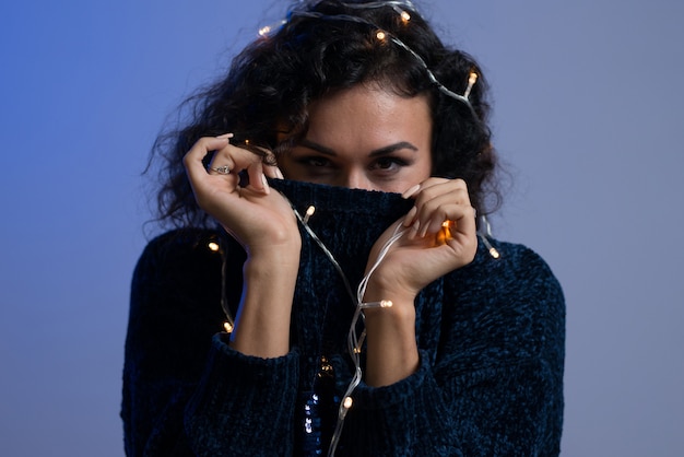 Jovem mulher com luzes brilhantes de Natal celebração.