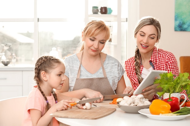 Jovem mulher com mãe e filha cozinhando na cozinha