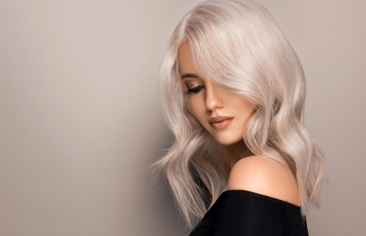 Jovem mulher com maquiagem glamourosa está cercando mechas enroladas de cabelo loiro Penteado ondulado tingido de loiro