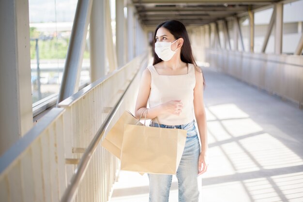 Jovem mulher com máscara facial está de pé ao ar livre