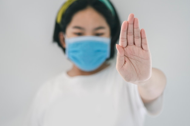 Jovem mulher com máscara médica protetora coloca a quarentena em casa para parar o coronavírus ou a pandemia de covid-19.