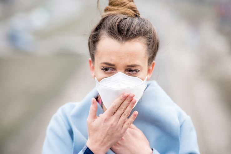 Foto jovem mulher com máscara protetora, se sentindo mal na cidade com poluição do ar proveniente do tráfego e da fabricação. conceito smog