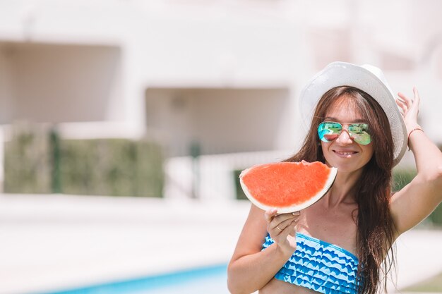 Jovem mulher com melancia relaxante ao ar livre nas férias de verão