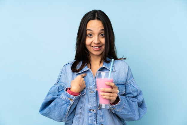 Jovem mulher com milk-shake de morango com expressão facial de surpresa
