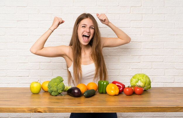 Jovem mulher com muitos legumes comemorando uma vitória