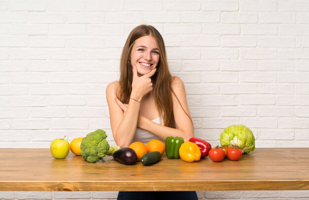 Jovem mulher com muitos vegetais rindo