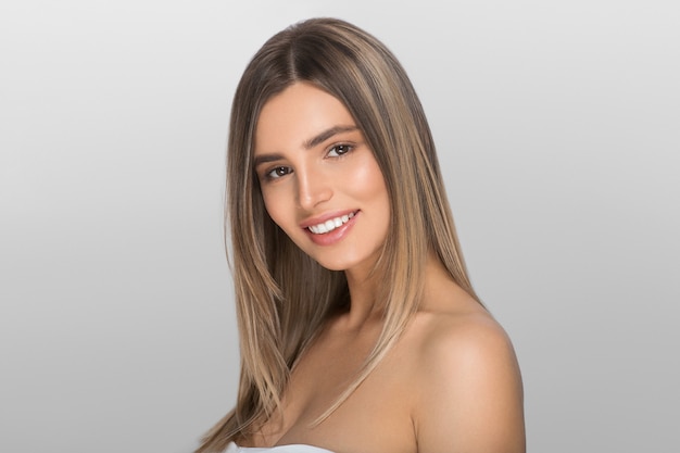 Jovem mulher com pele de beleza e penteado de beleza. Cor de fundo. cinza