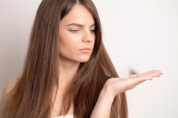 Jovem mulher com pente preocupada com queda de cabelo