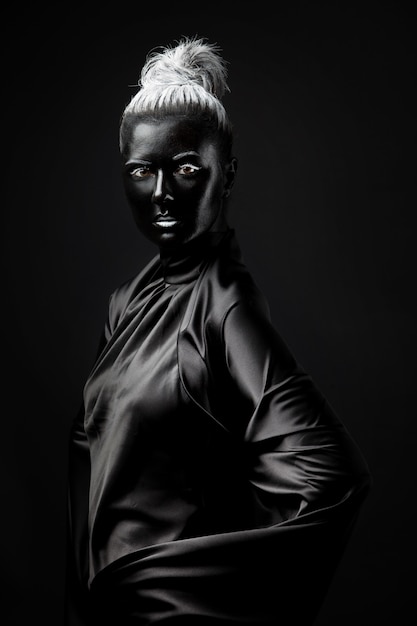 Jovem mulher com pintura no rosto preto sobre um fundo preto