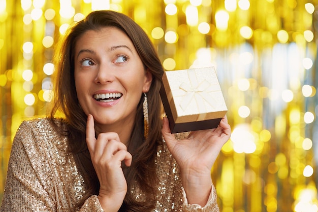 Jovem mulher com presente sobre fundo dourado