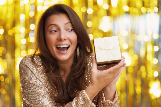 Jovem mulher com presente sobre fundo dourado