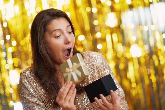 Jovem mulher com presente sobre fundo dourado