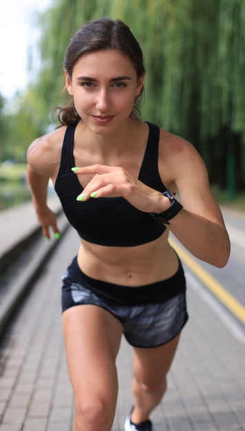 Jovem mulher com roupas esportivas, correndo durante o exercício ao ar livre.