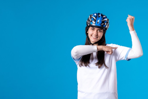 Jovem mulher com roupas esportivas e capacete na parede azul de frente