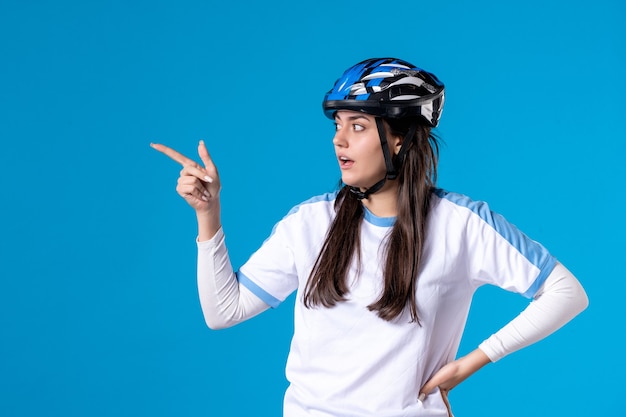 Jovem mulher com roupas esportivas e capacete na parede azul de frente