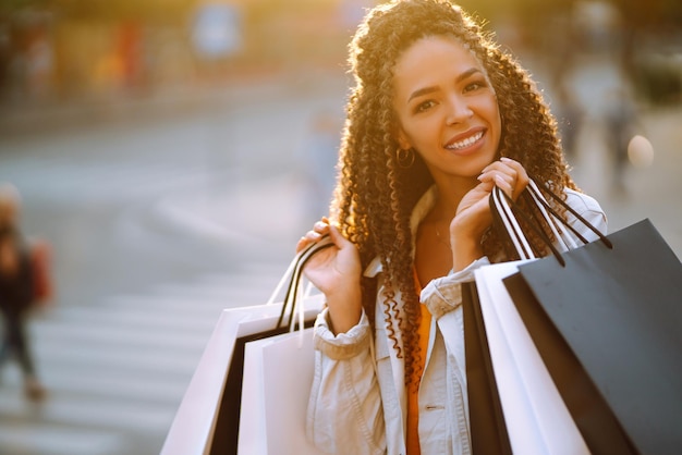 Jovem mulher com sacolas de compras andando na rua Venda de compras e conceito de pessoas felizes