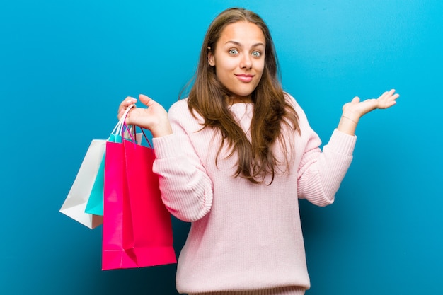 Jovem mulher com sacos de compras contra o fundo azul