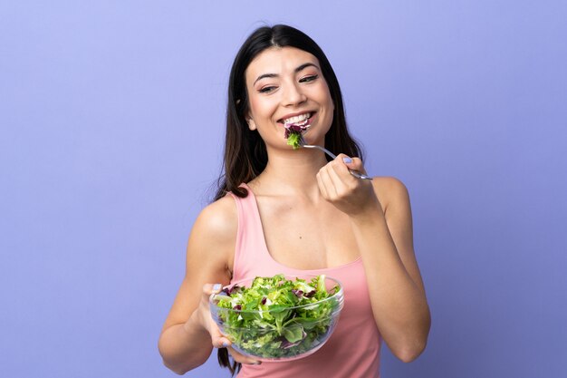 Jovem mulher com salada isolado parede roxa